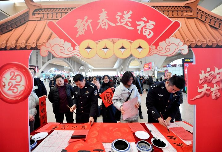 2025年1月14日，在石家庄站候车大厅，石家庄铁路公安处民警为旅客写春联。新华社记者 王晓 摄