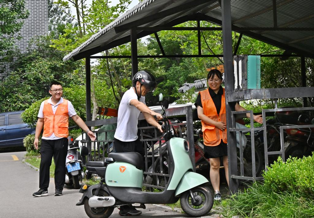 青岛胶州市少海澜山小区工作人员引导居民将电动自行车停进集中充电点。新华社记者李紫恒 摄