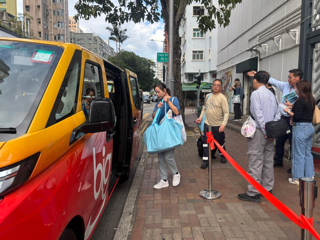 宏福苑受災(zāi)居民在庇護(hù)中心出來后，乘坐?？吭谙愀鄞笃疑鐓^(qū)會堂外的義載車輛（12月2日攝）。新華社發(fā)（許淑敏攝）