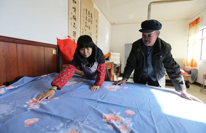 甘肃省定西市安定区内官营镇先锋村村民在整理刚领到的新床单（2025年11月19日摄）。初冬时节，当地开展“问暖”“送暖”“助暖”活动，保障困难群众温暖过冬。新华社发（王克贤摄）