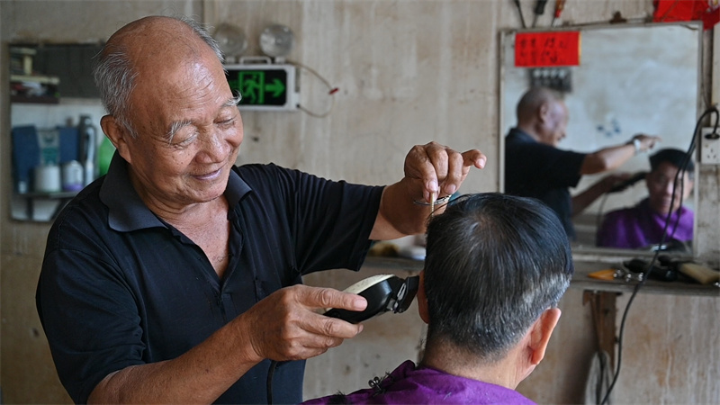 黄锡然把老式理发椅放平,客人应声躺下,眯上双眼准备享受放松身心的刮