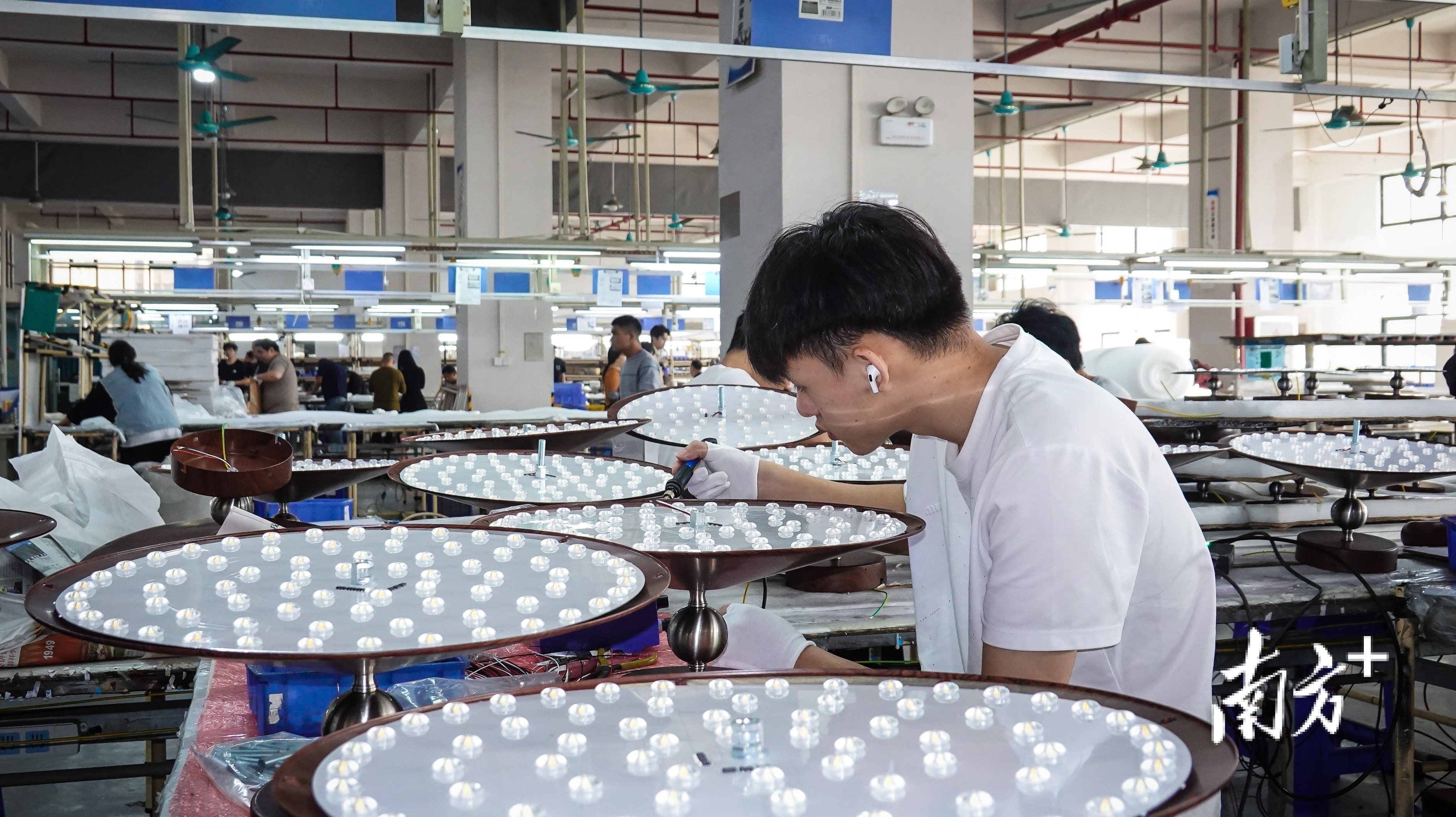 中山市海弗来照明科技有限公司车间内，工人正在对灯饰进行装配作业。