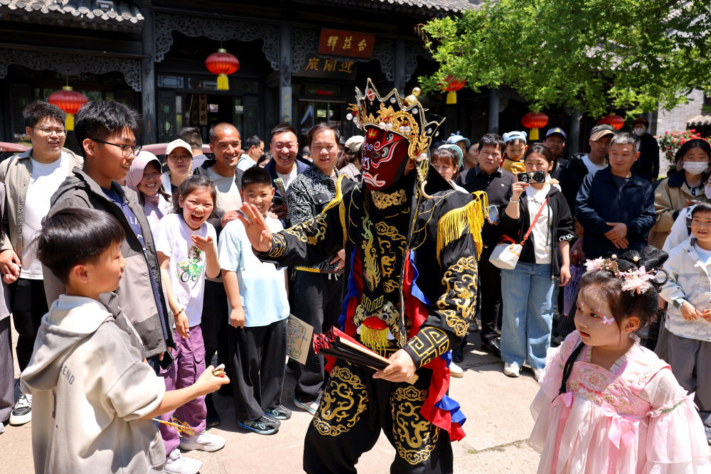 5月3日,在山东省枣庄市台儿庄古城,艺人与游客互动。新华社发(孙中喆摄)