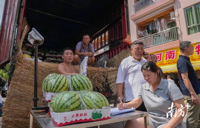 7月23日,广州番禺,王如波(左三)在货车尾部,正在打电话沟通西瓜的订购。 7月23日,广州番禺,王如波(左三)在货车尾部,正在打电话沟通西瓜的订购。
