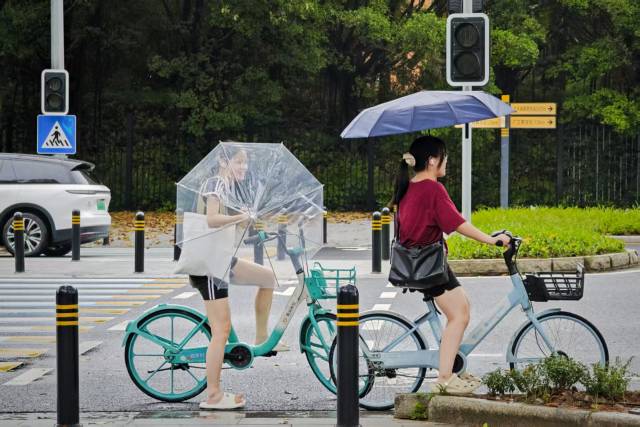 在番禺大学城中环西路，降雨时断时续，大学生们打伞出行。